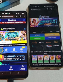 Two smartphones are displayed on a white surface, both showing gambling websites with colorful graphics, text, and various options for logging in and accessing games. The screens are bright and filled with promotional content related to casino and slot games.